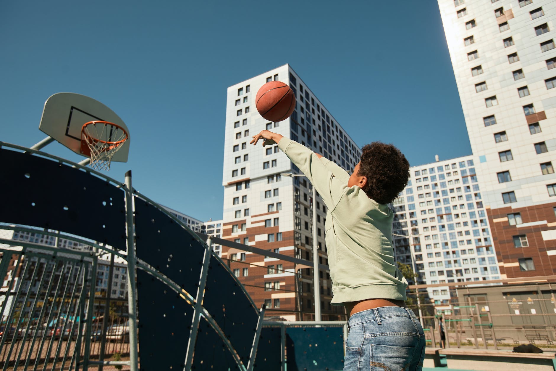 back view shot of a young boy shooting the ball on the ring
